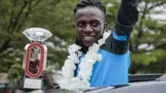 Burundian athlete Francine Niyonsaba who set new world record of women's 2000m with 5 minutes 21 seconds and 56 hundredths of a second reacts to people from a car in Bujumbura, Burundi.