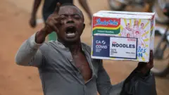 Wani mutum dauke da katan din indomie