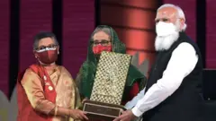 শেখ রেহানার হাতে শেখ মুজিবকে ভারতের দেয়া গান্ধী শান্তি পুরস্কার তুলে দিচ্ছেন নরেন্দ্র মোদী