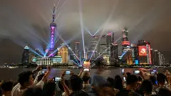 Spectators look at a light show on the Bund promenade in Shanghai