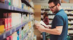 Homem olha rótulos de produtos em supermercado