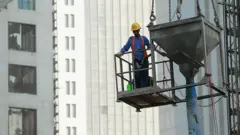 দোহায় এক নির্মাণ প্রকল্পে কাজ করছেন একজন অভিবাসী শ্রমিক।