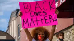 Seorang perempuan memegang spandung Black Lives Matter
