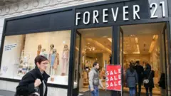 Mulher passa em frente de loja da Forever 21