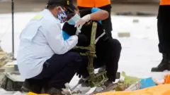 Indonesian officials inspect suspected debris from the plane