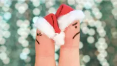 Dedos com rostos pintados e chapéu de papai noel de costas um para o outro