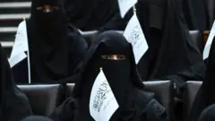 A veiled woman holiding a Taliban flag attends a pro-Taliban event at a Kabul university.