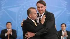Retrato de Rogério Marinho e Jair Bolsonaro abraçados em cerimônia no Palácio do Planalto em 2020