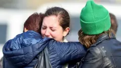 Women react as they embrace each other after the attack