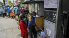 People stand in a queue to buy kerosene oil used in cooking stoves in Colombo on August 31, 2021 following Sri Lanka's declaration of state of emergency over food shortages as private banks ran out of foreign exchange to finance imports.