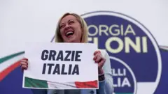 Leader of Brothers of Italy Giorgia Meloni holds a sign at the party's election night headquarters