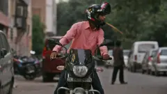 Un motociclista escupe en la calle en Nueva Delhi.
