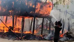 -রোহিঙ্গা বসতবাড়িতে আগুন নেভানোর চেষ্টা করছে একজন