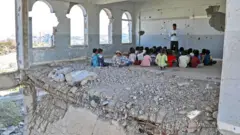 यमनमा बालबालिक नयाँ शैक्षिक सत्रको पहिलो दिन विद्यालयमा पढ्दै।
