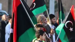متظاهرون يحملون العلم الليبي