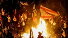 Protesters waving flags around fires in Tel Aviv