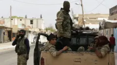 Turkish-backed Syrian fighters sit in the back of a truck in the Syrian border town of Tal Abyad on October 17, 2019