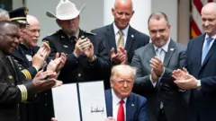 Donald Trump mostrando su orden ejecutiva firmada