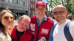 Litvanyalı turistler Vitalijus ve Laura Zuikauskas ile bir Big Issue satıcısı