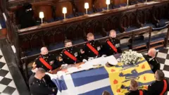 Queen Elizabeth II watches as the coffin of the Duke of Edinburgh is placed St George"s Chapel, Windsor Castle, Berkshire during his funeral service.