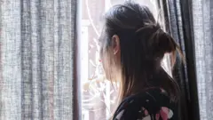 መስኮት አጠገብ የቆመች ሴት
