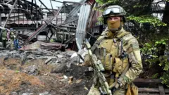 A Russian serviceman stands guard at the destroyed part of the Ilyich Iron and Steel Works in Ukraine's port city of Mariupol