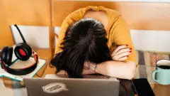 Mujer con la cabeza agachada en su puesto de trabajo.