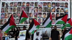 Protesters lift national flags during a rally in Ramallah city in the occupied West Bank, in support of Gaza and of Palestinian prisoners in Israeli jails, on 14 November, 2023