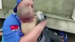Still image of rescue worker holding baby