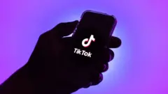 One illustration of hand wey hold phone show di TikTok logo