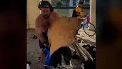 Hombre tirando las cosas de un sin techo a la basura