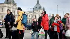 People fleeing the Russian military campaign in eastern Ukraine wait to board a bus that will take them to Poland on 9 April 2022 in Lviv, Ukraine