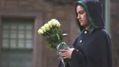A Warden of the Palace of Holyroodhouse holds flowers