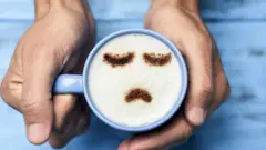 Una taza de café con un cara triste