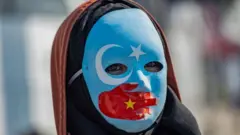 A protester against China's actions in Xinjiang wears a mask with the colours of the flag of East Turkestan