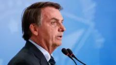 Bolsonaro de perfil, falando em microfone durante cerimônia