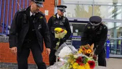 Police officers leave flowers outside Croydon Custody Centre in south London
