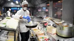 Kitchen staff at the Kebabish Grill restaurant in Glasgow wear masks as they prepare foo