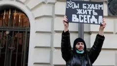 Человек у суда с плакатом "Мы будем жить всегда"