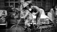 A man stands on a platform attached to a moving bicycle