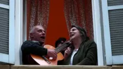 Hombre y mujer cantando desde una ventana en Italia