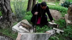 El arzobispo Hosam Naoum inspecciona una tumba profanada en el cementerio protestante del Monte Sión en Jerusalén (4 de enero de 2023).
