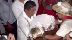 Mayor holding crocodile dressed in bridal outfit