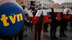 Протесты против закона о СМИ в Варшаве. В руках людей плакаты с логотипом TVN и буквы слова VETO