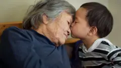 A Chinese child kisses an older woman - stock image