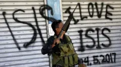 IŞİD askeri Işid'i seviyorum yazan bir grafitinin önünde