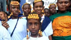 Girls with matching braids and clothes pose for the camera.