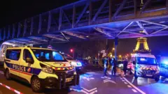 Scene showing emergency vehicles and lit-up Eiffel Tower in background