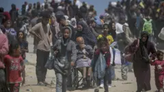 Interno raseljeni Palestinci koji su pobegli iz severnog pojasa Gaze šetaju putem Al Rašida dok pokušavaju da se vrate iz južnog pojasa Gaze, april 2024.