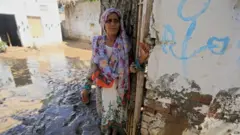 पुरात घराशेजारी थांबलेली एक महिला